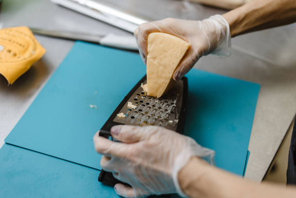 mulher esfrega queijo em uma tábua de cortar
 - Foto, Imagem
