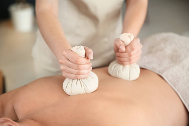 Man receiving herbal bag massage in spa salon, closeup - Fotó, kép