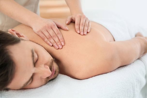 Handsome man receiving back massage in spa salon - Foto, immagini