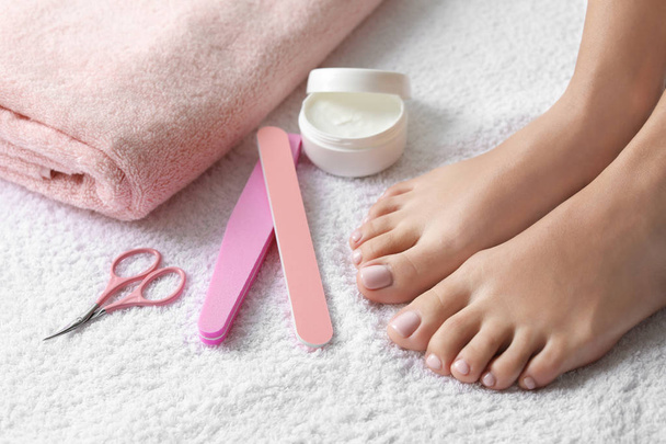 Woman with beautiful feet and pedicure accessories on white towel, closeup. Spa treatment - 写真・画像