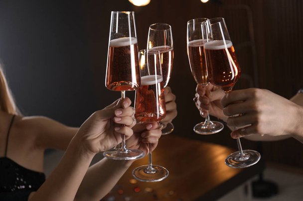 Friends clinking glasses with champagne on blurred background, closeup - Foto, Imagen