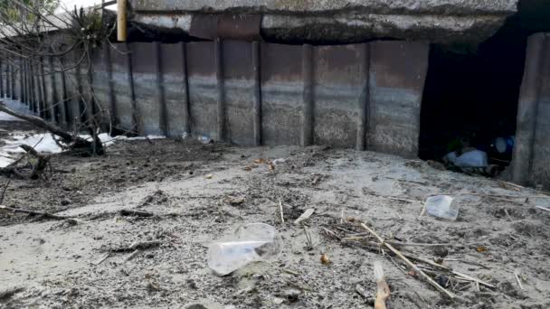 Plastikflaschen und Gläser am Sandstrand. Schmutzwasser, in dem sllichny Müll schwimmt. weißer Schaum am Ufer - Filmmaterial, Video
