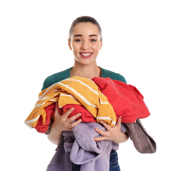 Happy young woman holding pile of dirty laundry on white background - Photo, Image
