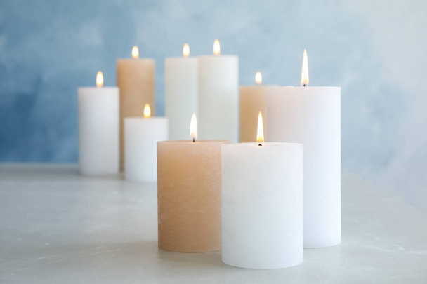 Burning candles on table against color background. Space for text - Foto, Imagem