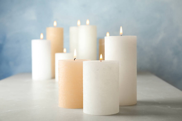 Burning candles on table against color background - Фото, изображение