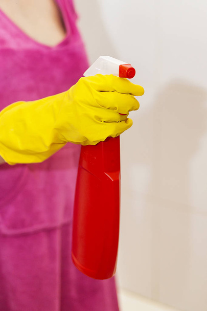 Mujer con spray limpiador. Ama de casa sosteniendo botella de spray rojo en el baño. Baño de limpieza
 - Foto, Imagen