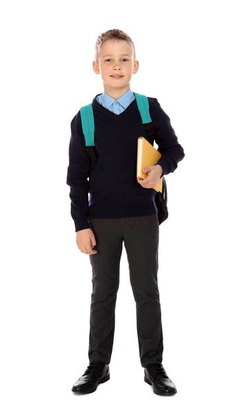 Full length portrait of cute boy in school uniform with book and backpack on white background - Foto, afbeelding