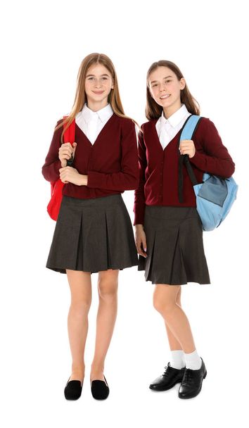 Full length portrait of teenage girls in school uniform with backpacks on white background - Фото, изображение