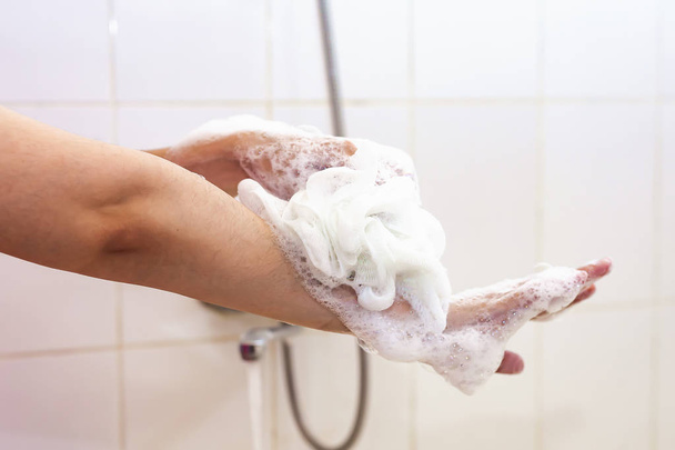 Γυναίκα πλένει τα χέρια με σφουγγάρι στο μπάνιο. Θηλυκό πλύσιμο χεριών με αφρώδες σφουγγάρι στο μπάνιο. Φροντίδα σώματος και καθαρή έννοια - Φωτογραφία, εικόνα