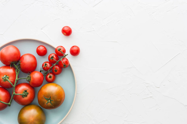 Different types of tomatos on a plate on a white background - Foto, afbeelding