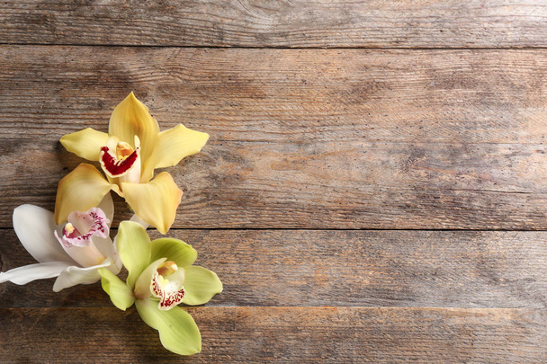 Beautiful tropical orchid flowers on wooden background, flat lay. Space for text - Фото, зображення