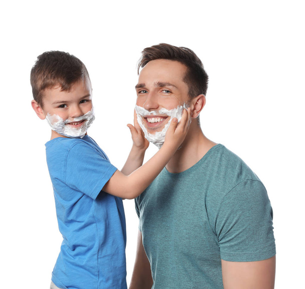Happy dad and son with shaving foam on faces against white background - Fotoğraf, Görsel