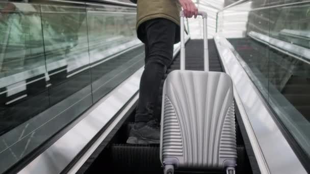 Ο άνθρωπος με τη βαλίτσα στέκεται στο κινούμενο κυλιόμενες σκάλες, κοντινό-up θέα των ποδιών - Πλάνα, βίντεο