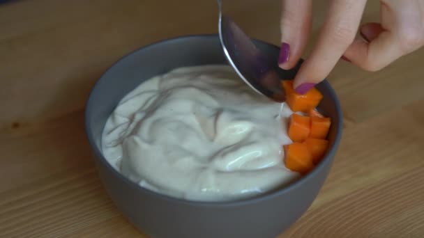 Closeup shot of a process of making a smoothie bowl with papaya, dragon fruit, granola, dried cherry, and pumpkin seeds - Filmagem, Vídeo
