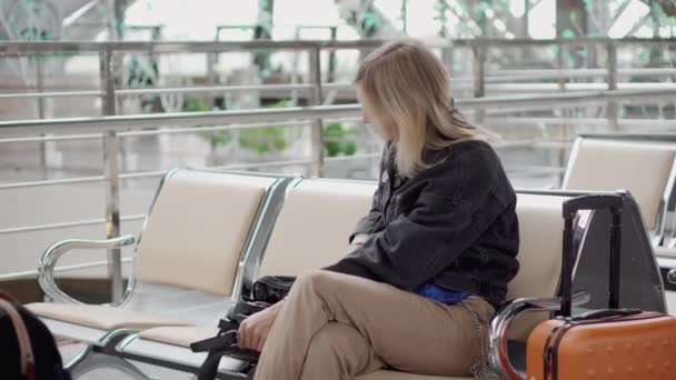 Pasażer dziewczyna bierze tabletki z worka, siedząc w poczekalni lotniska - Materiał filmowy, wideo