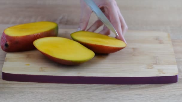 Vrouwelijke chef-koks handen slice mango op houten snijplank. - Video