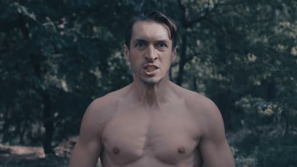 Hombre agresivo con un torso desnudo gritando furiosamente en el bosque
 - Metraje, vídeo