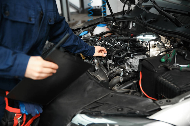 Technician checking modern car at automobile repair shop, closeup - Φωτογραφία, εικόνα