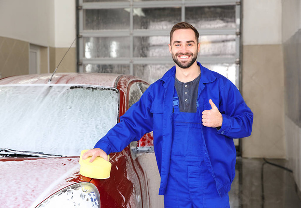 Portrait of worker with sponge near auto at car wash - Foto, afbeelding