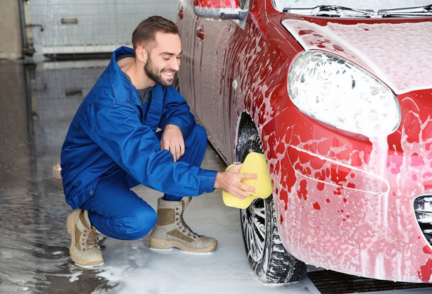 Young worker cleaning automobile wheel at car wash - Фото, зображення