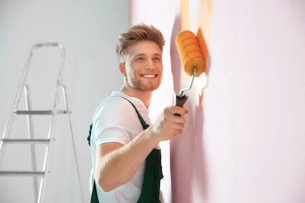 Professional decorator painting wall indoors. Home repair service - Zdjęcie, obraz