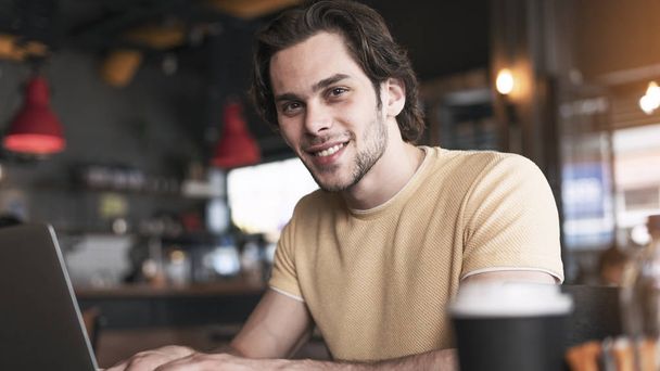 Junger Mann benutzt Laptop in Café - Foto, Bild