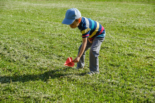 Jongen spelen met een speelgoed rode vliegtuig in Park op een zonnige dag - Foto, afbeelding