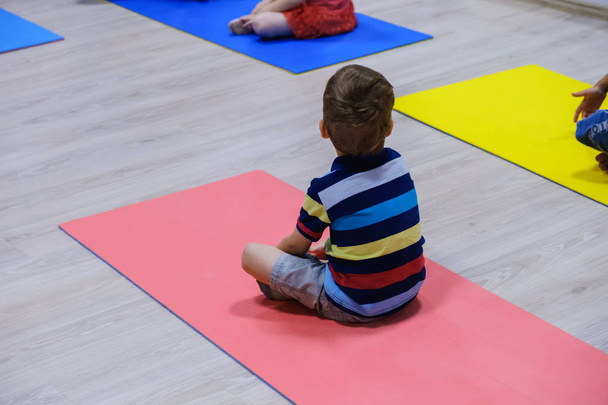 Cute sporty kid exercising on yoga mats in gym, children sport school concept - Photo, image