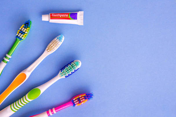 kleine tandpasta en verschillende tandenborstels van Top View op blauw - Foto, afbeelding