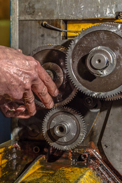 産業機械クローズアップで労働者の手が付いているギヤ金属車輪 - 写真・画像