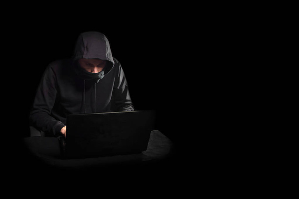 Pirate informatique avec ordinateur portable déclenchant une cyberattaque, isolé sur noir
 - Photo, image