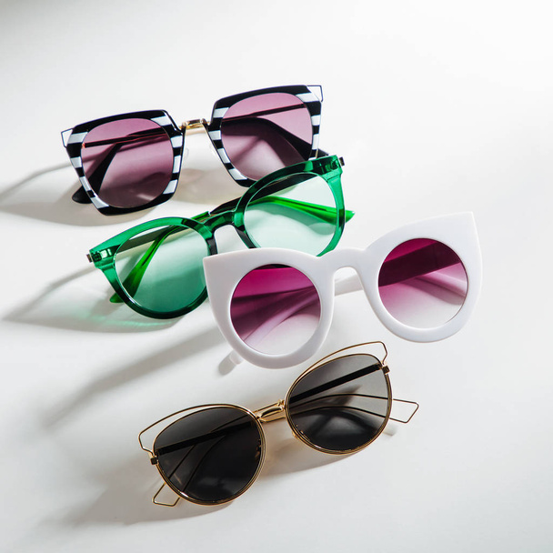Set of Stylish sunglasses with bright sunlight on white background. Flat lay, top view. Summer fashion concept - 写真・画像