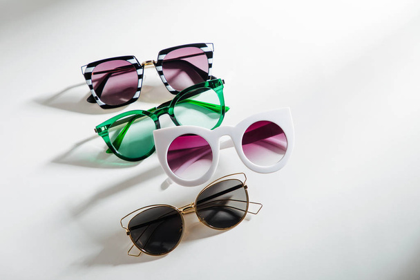 Set of Stylish sunglasses with bright sunlight on white background. Flat lay, top view. Summer fashion concept - 写真・画像