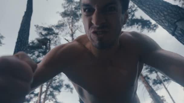 Aggressivo uomo a torso nudo batte brutalmente mentire avversario all'aperto nella foresta
. - Filmati, video