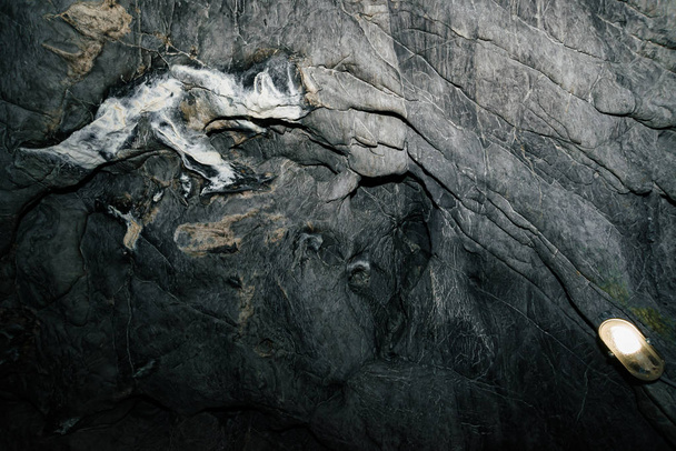 Piękna Jaskinia. Widok z wnętrza ciemnego lochu. Teksturowane ściany jaskini. Obraz tła podziemnego tunelu. Wilgoć wewnątrz jaskini. Oświetlenie wewnątrz jaskini na wycieczki. - Zdjęcie, obraz