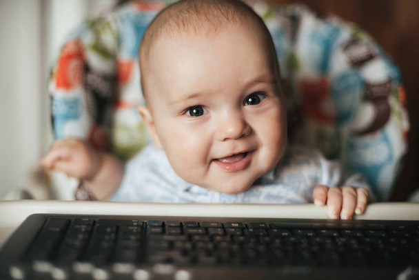 portrait of a cute baby boy sitting and playing with a keyboard - Photo, Image