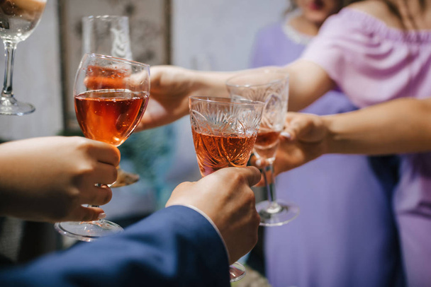 hands of a group of friends clinking glasses of alcoholic beverage and toasting and congratulating - Photo, Image