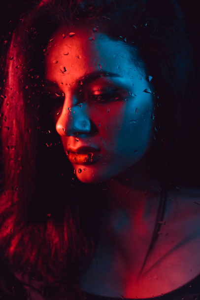Portret smutnej dziewczyny z naciskiem na szkło z krople deszczu - Zdjęcie, obraz