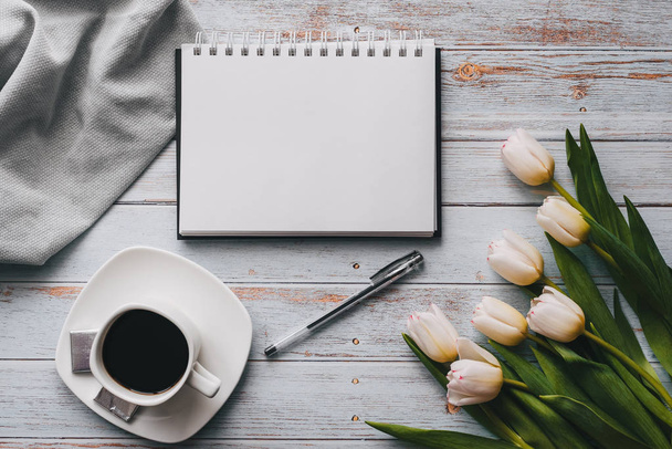 Buquê de tulipas brancas com um caderno vazio e xícara de café em um fundo de madeira
 - Foto, Imagem