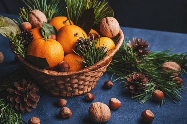 Mandarinas, nueces y avellanas decoradas con piñas y ramas - Foto, Imagen