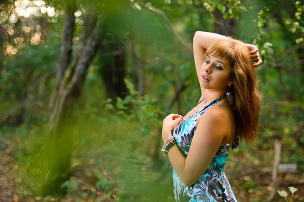 Caucasian girl in blue dress posing in forest in summer - Foto, Imagen