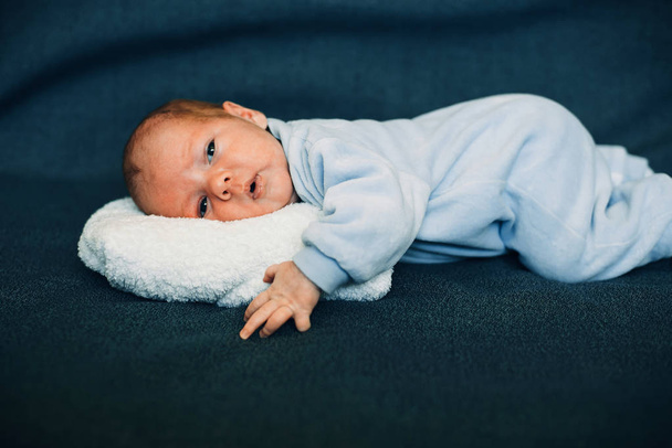 νεογέννητο αγοράκι που βρίσκεται στο λευκό μαξιλάρι βελούδου - Φωτογραφία, εικόνα