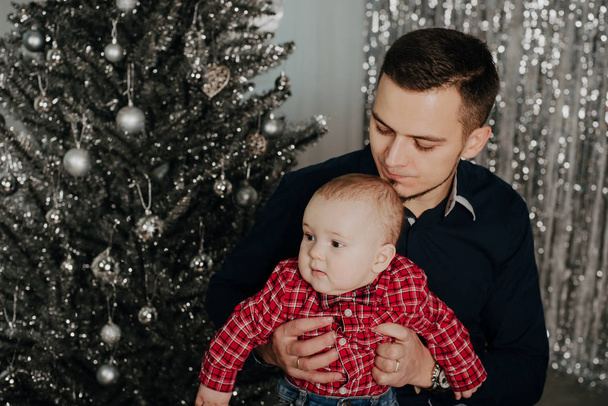 little boy child in the arms of his father on the background of the Christmas tree - Foto, afbeelding