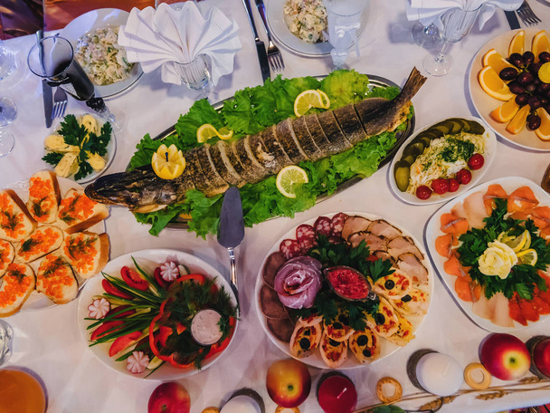 traditionele Russische keuken met gebakken gevulde snoek en andere hapjes op de feestelijke tafel in het restaurant - Foto, afbeelding