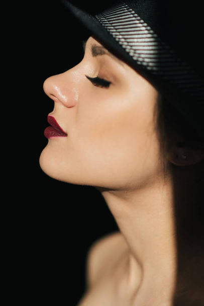 ritratto di moda di profilo di una giovane ragazza sexy in un cappello nero con rossetto rosso
 - Foto, immagini