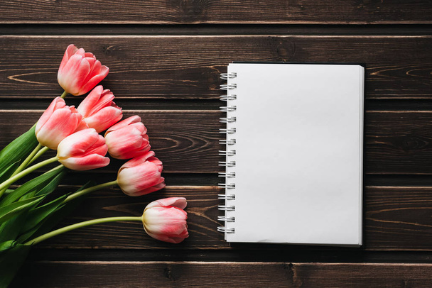 tulipanes de flores rosadas con bloc de notas en blanco en la mesa de madera para tarjeta de felicitación
 - Foto, imagen