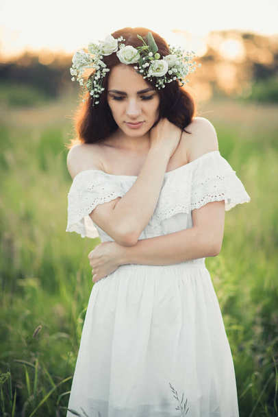 retrato de chica morena atractiva en vestido blanco y con corona floral
 - Foto, imagen