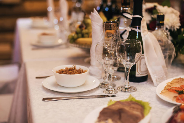 стаканы и тарелки с закусками на праздничном столе
 - Фото, изображение