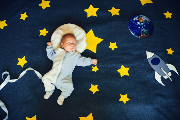niño pequeño bebé durmiendo en un traje del astronauta en el fondo del cielo estrellado
 - Foto, imagen