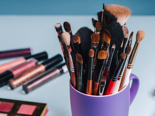 conjunto de escovas de maquiagem profissional no fundo de uma paleta com sombras coloridas e cosméticos
 - Foto, Imagem